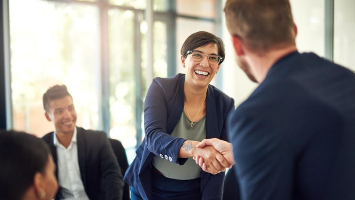 white female smiling shaking hands with white male